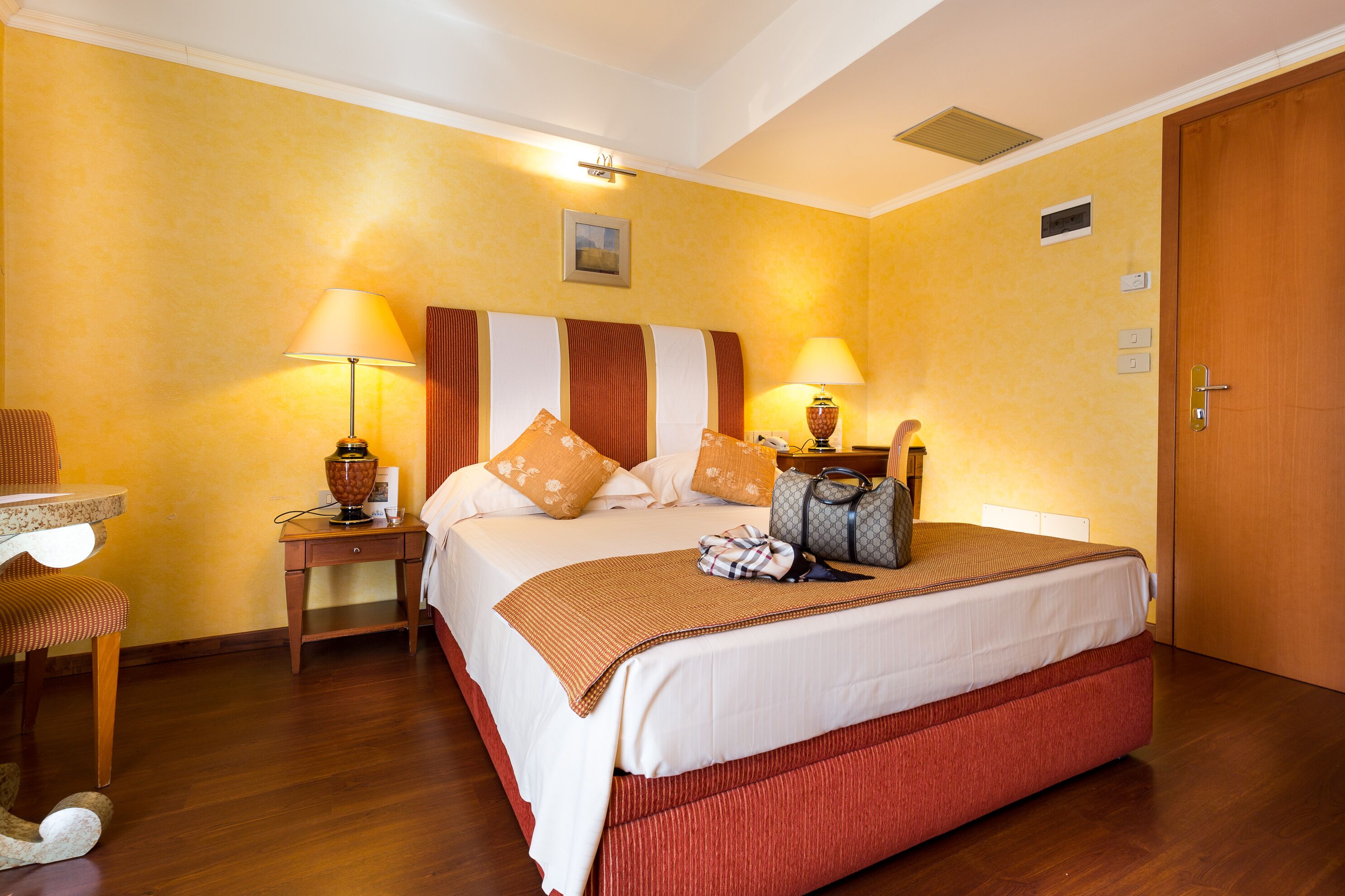 A hotel room with a bed, two bedside tables, a chair, and a lamp.