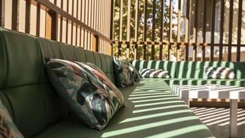 A green outdoor seating area with patterned cushions and a white table.