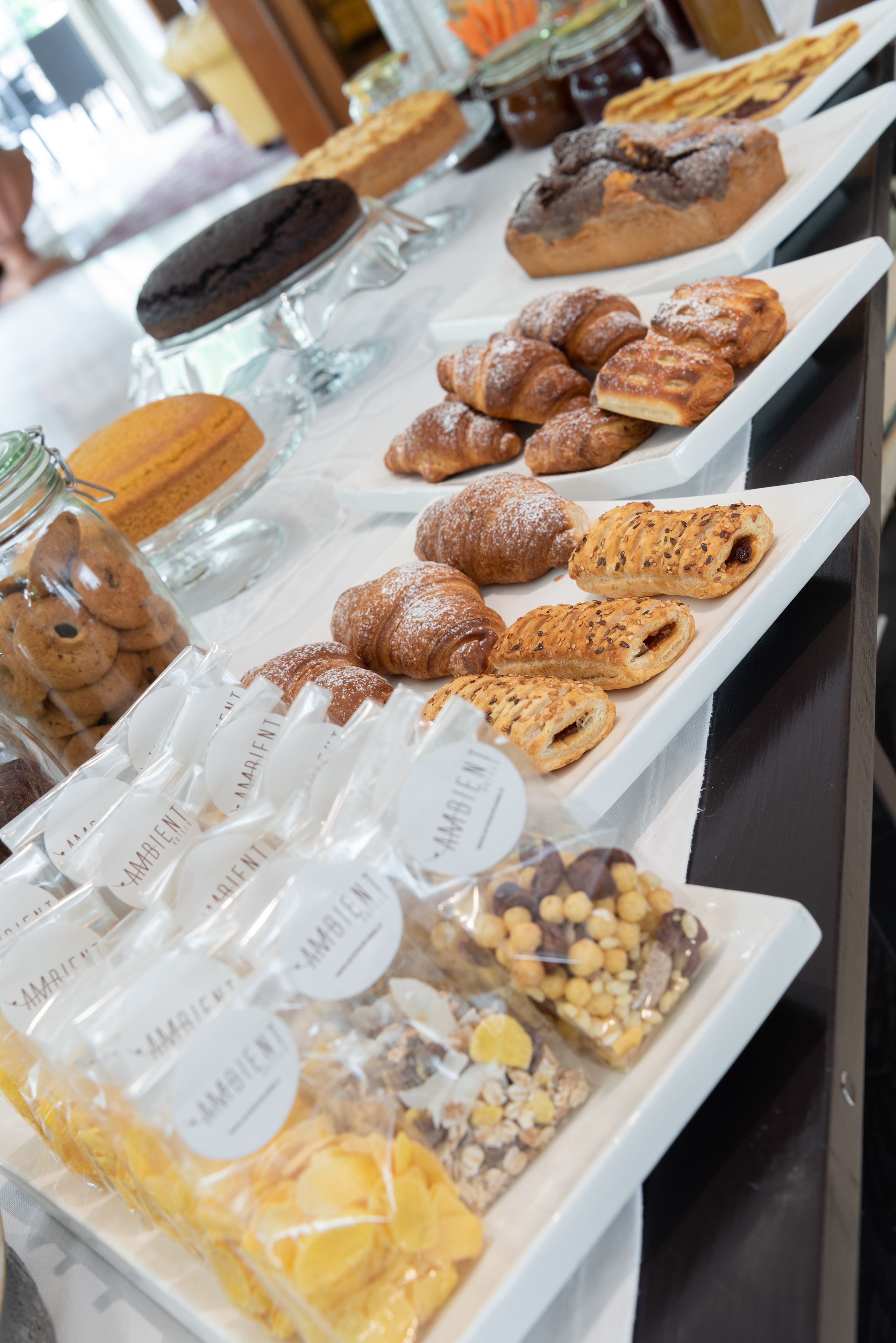 Una mesa de buffet con diversos pasteles y postres, incluyendo croissants, galletas y tartaletas de frutas.