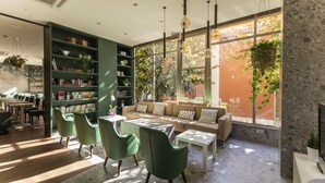 A modern library with green chairs, a sofa, and a large window with plants. - BIO BOUTIQUE HOTEL XU' (Rimini)