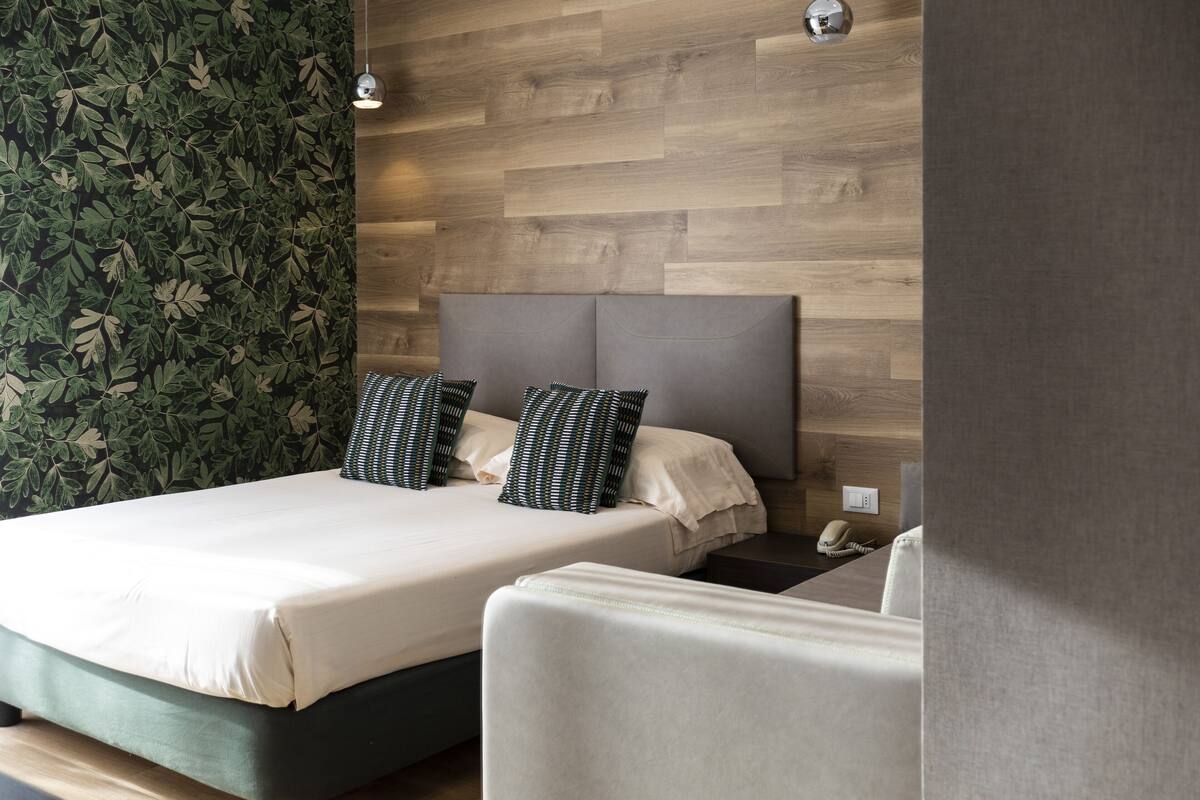 Un dormitorio moderno con una cama grande, dos almohadas, una mesita de noche y un teléfono.