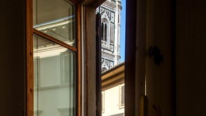 A window with wooden frames and a view of a building with architectural details. - Hotel Costantini (Florence)