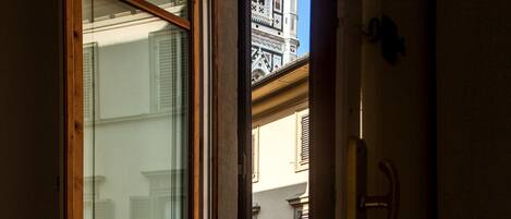 Una ventana con marcos de madera y vistas a un edificio con detalles arquitectónicos.