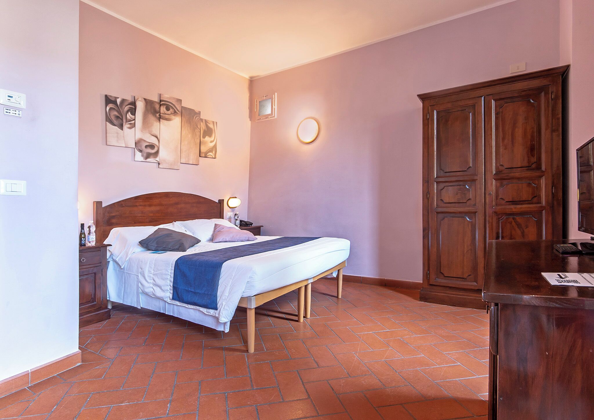 Une chambre à coucher avec un lit, une table de chevet, une lampe et une armoire.