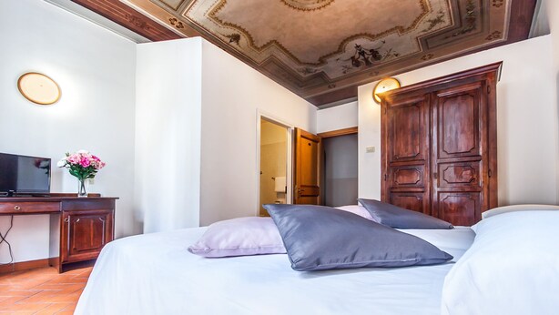 A hotel room with a bed, a TV, a desk, and a wooden wardrobe. - Hotel Costantini (Florence)
