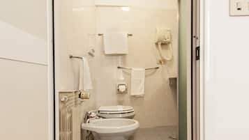 A bathroom with a toilet, a towel rack, a hand dryer, and a shower area.