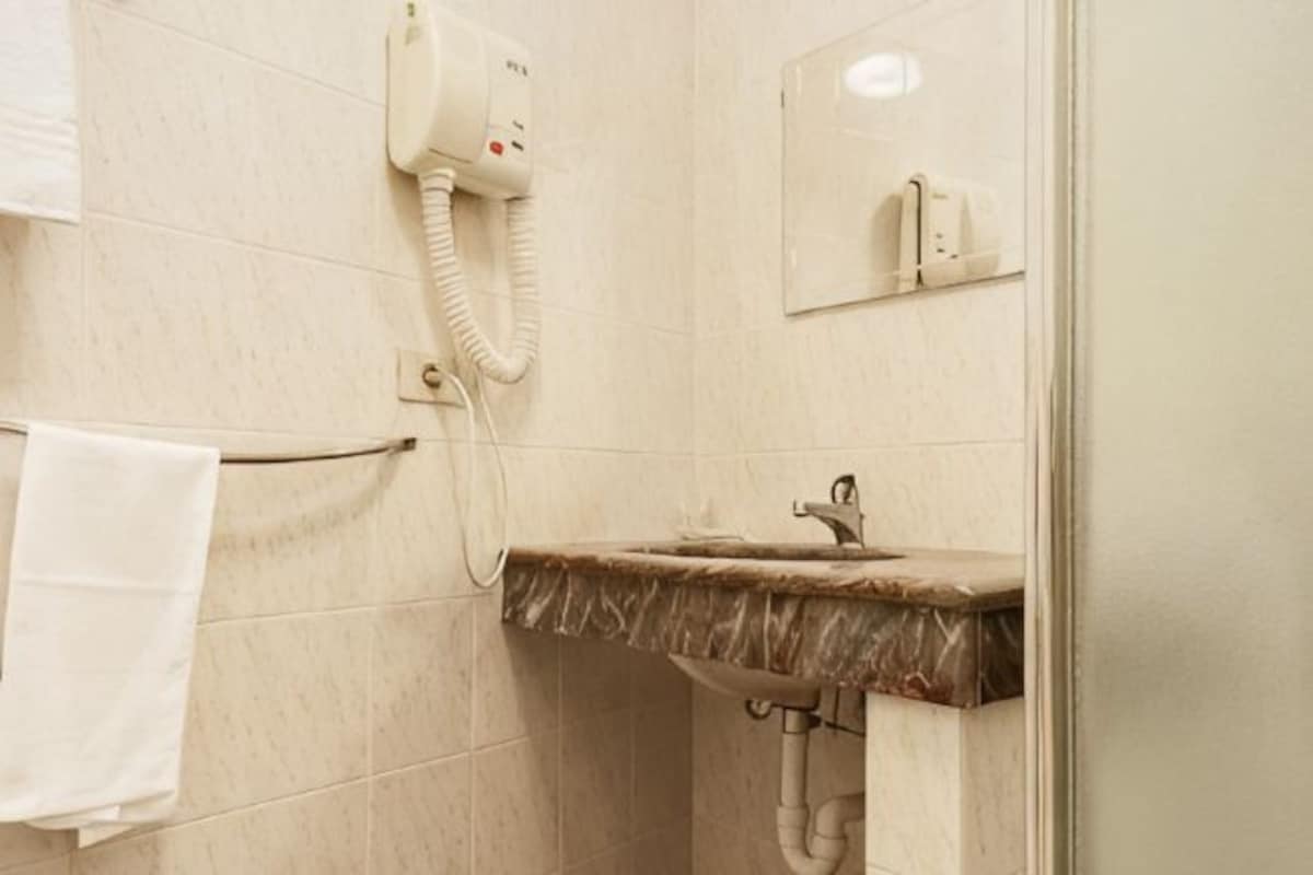 Un baño con lavamanos de mármol, perchero y secador de pelo montado en la pared.