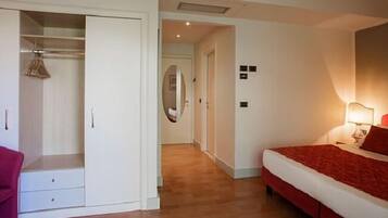 Un dormitorio con cama, armario, espejo y lámpara de noche.