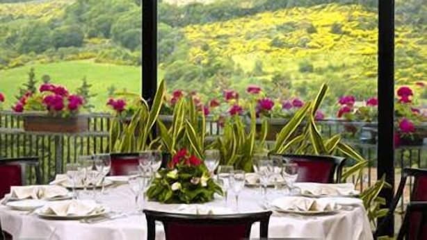 A table set for dining with a view of a green landscape and yellow flowers. - Hotel Dei Duchi (Spoleto)