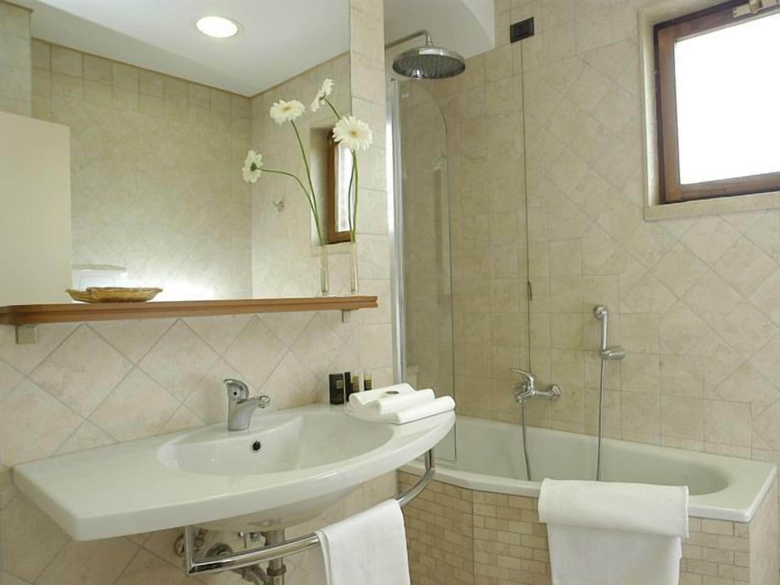 Une salle de bain équipée d’un lavabo, d’un miroir, d’une douche et d’une baignoire.