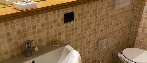 A bathroom with a sink, bidet, and toilet, tiled in beige and white.