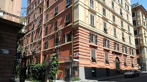 Un hotel de varios pisos con un estilo arquitectónico clásico, que cuenta con una entrada destacada con un camino de acceso porticado y una señal visible.