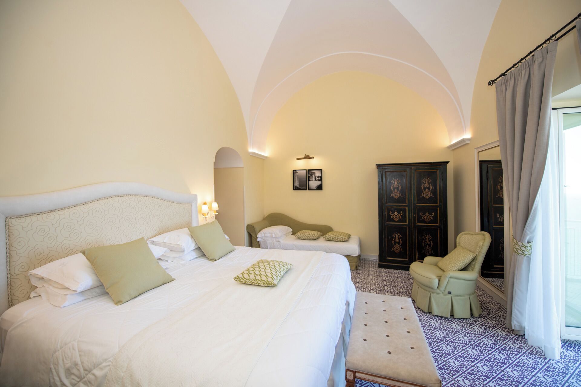 A hotel room with two beds, a sitting area, and a wardrobe.
