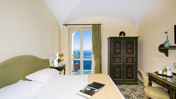 Ein Hotelzimmer mit Bett, Schreibtisch, Stuhl, Kleiderschrank und Meerblick.