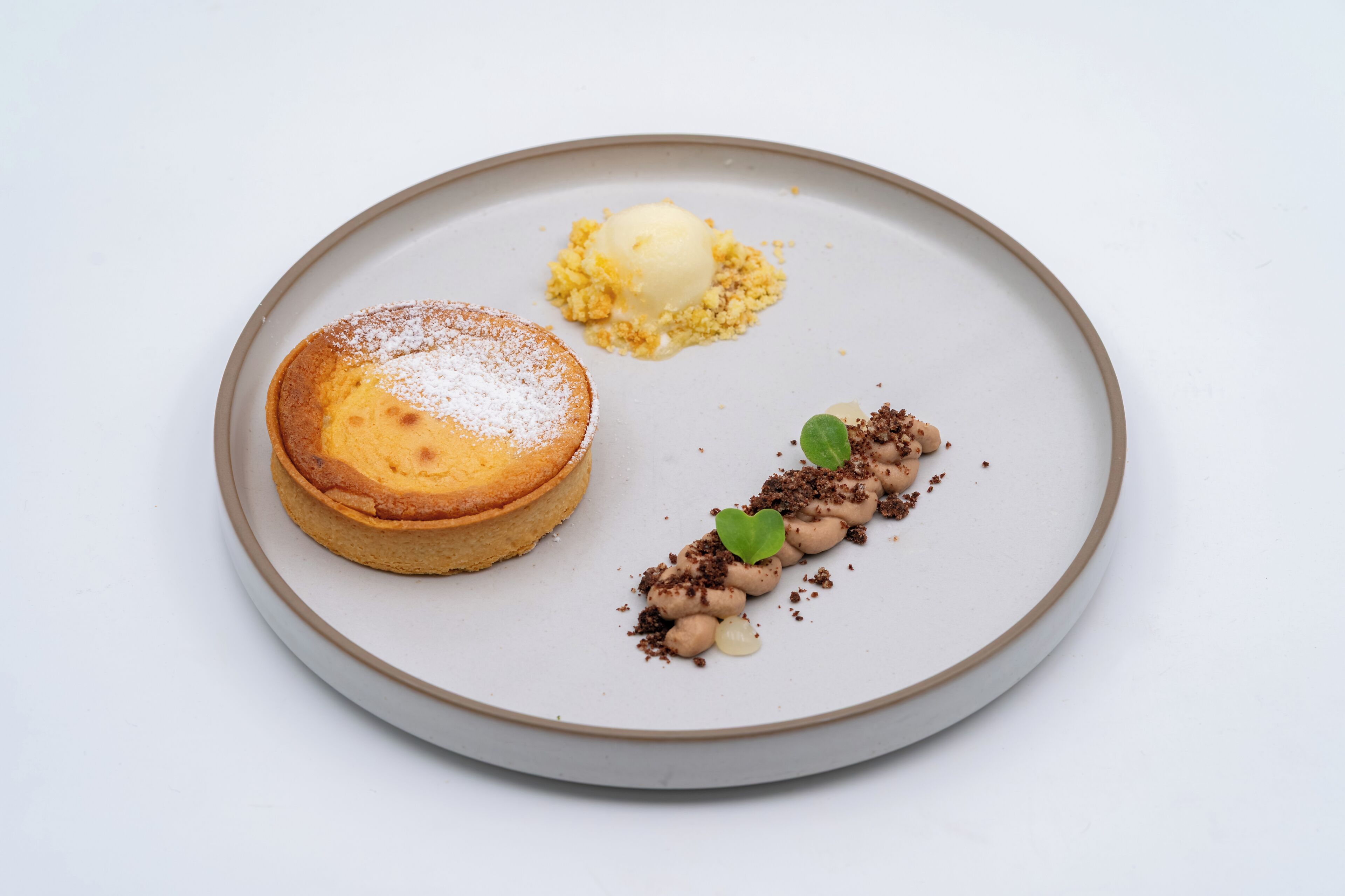 A dessert plate with a cake, ice cream, and chocolate garnish.