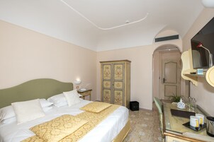 Habitación de hotel con cama, cómoda, espejo y puerta que da a otra habitación.