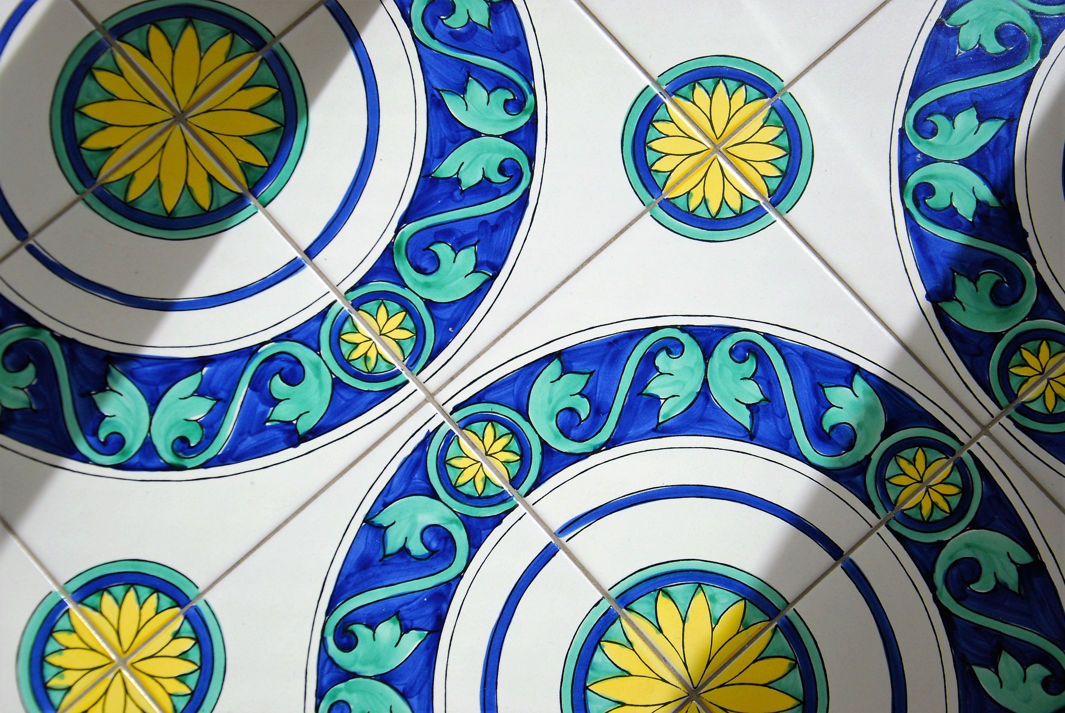 A close-up of a tiled wall with a repeating pattern of blue and yellow floral designs.