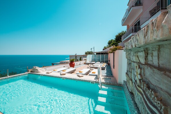 Piscine extérieure en saison, parasols, chaises longues