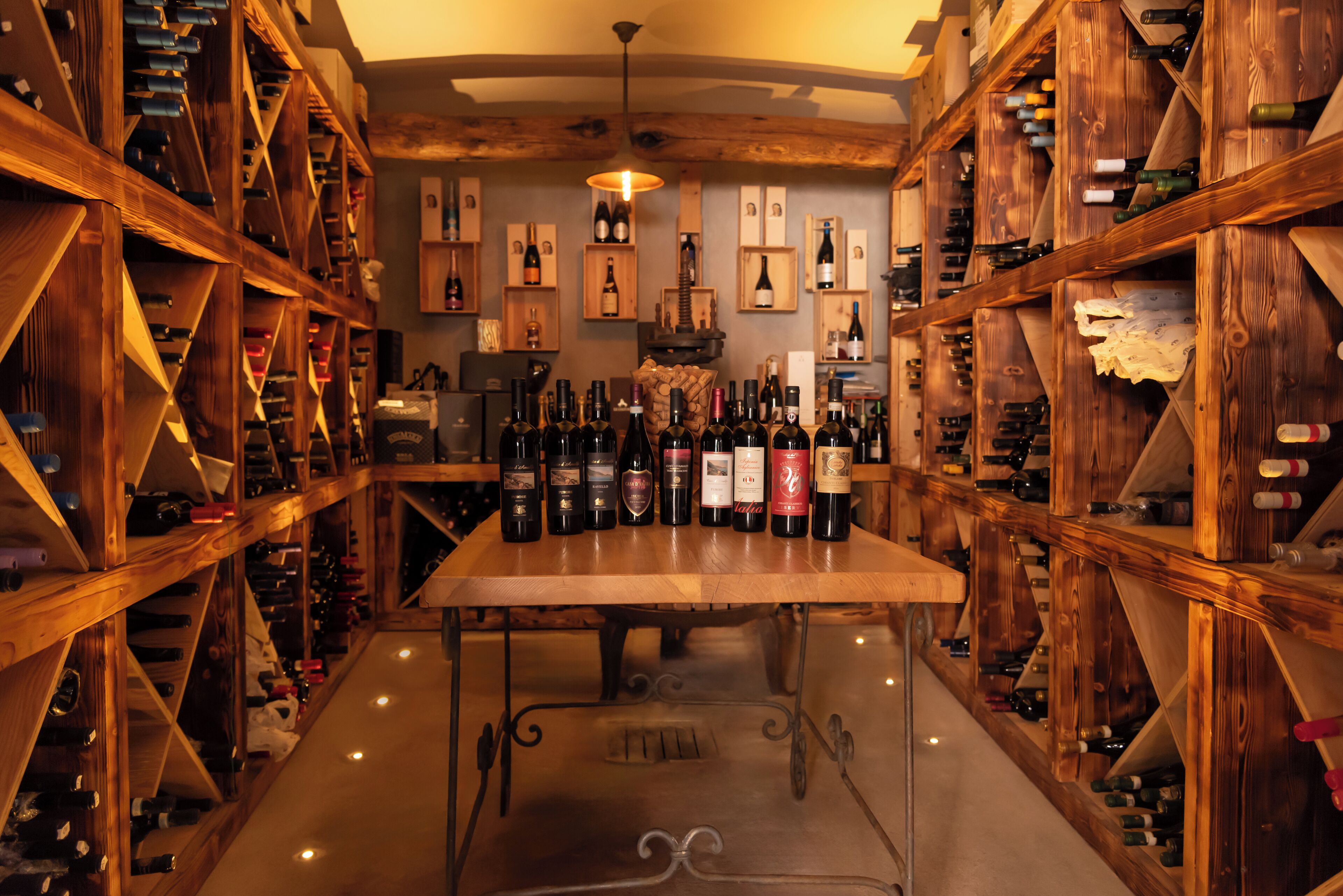 A wine cellar with wooden racks and a central table displaying various wine bottles.
