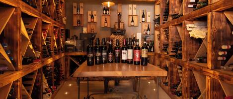 A wine cellar with wooden racks and a central table displaying various wine bottles.