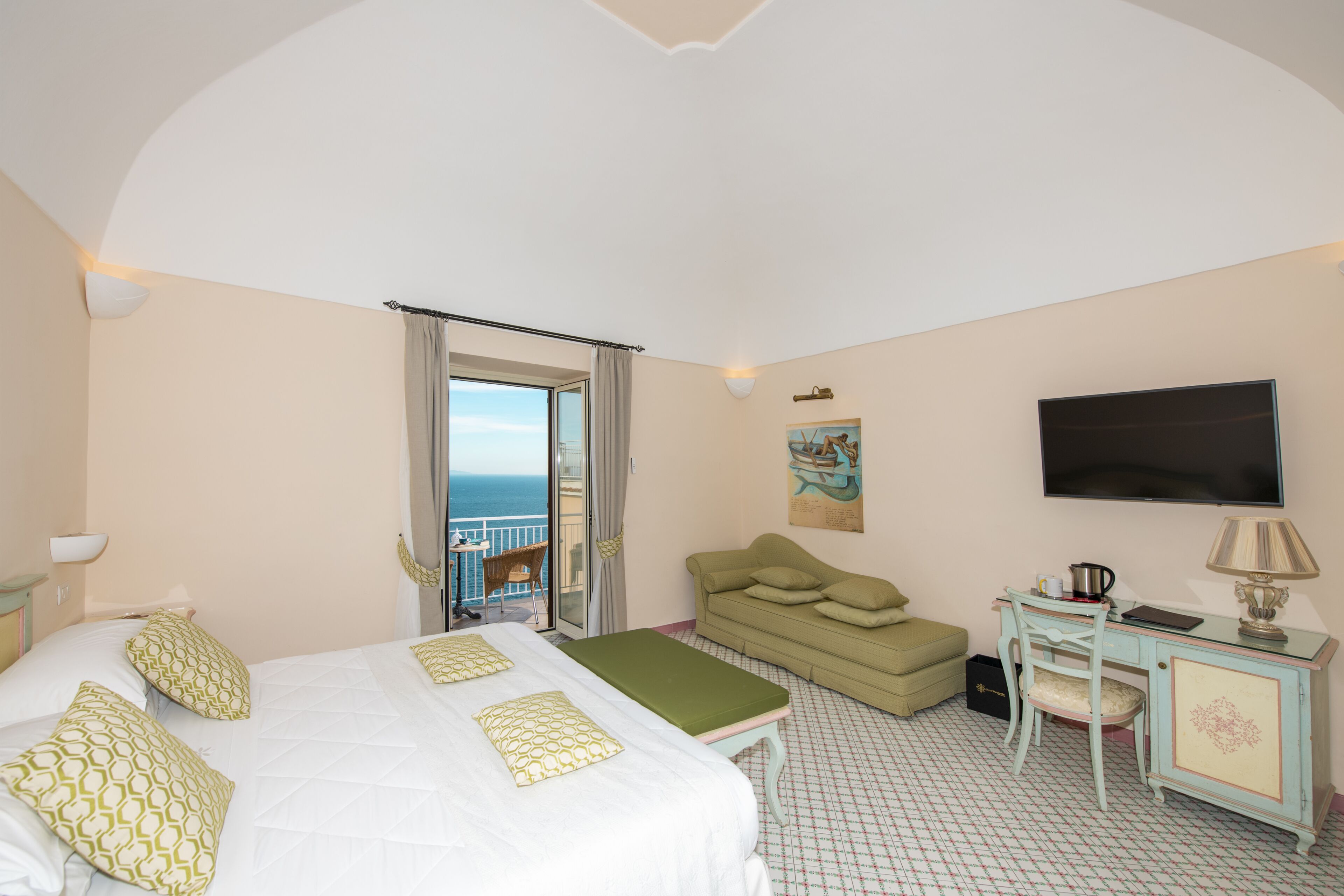 Une chambre d’hôtel avec un lit, un bureau, un canapé et une télévision.