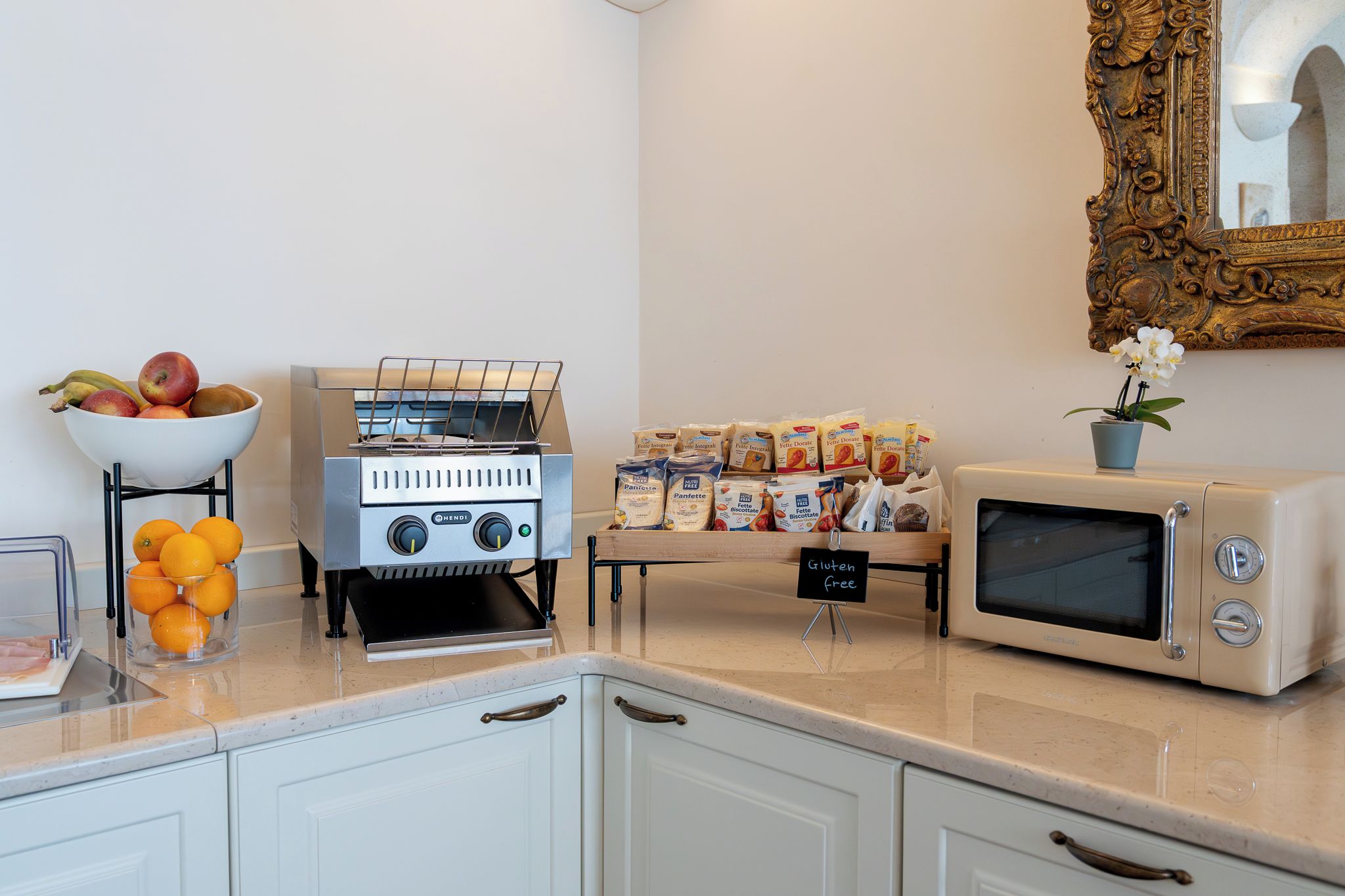 Una kitchenette con estufa a gas, microondas y un bol de fruta en la encimera.