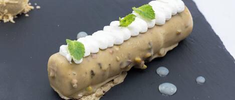 A dessert on a slate plate with mint leaves and a scoop of ice cream in the background.