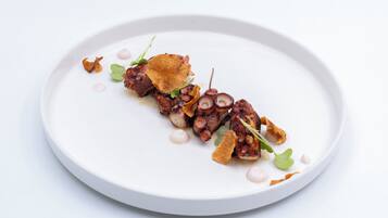 Un plato blanco con pulpo y guarniciones.