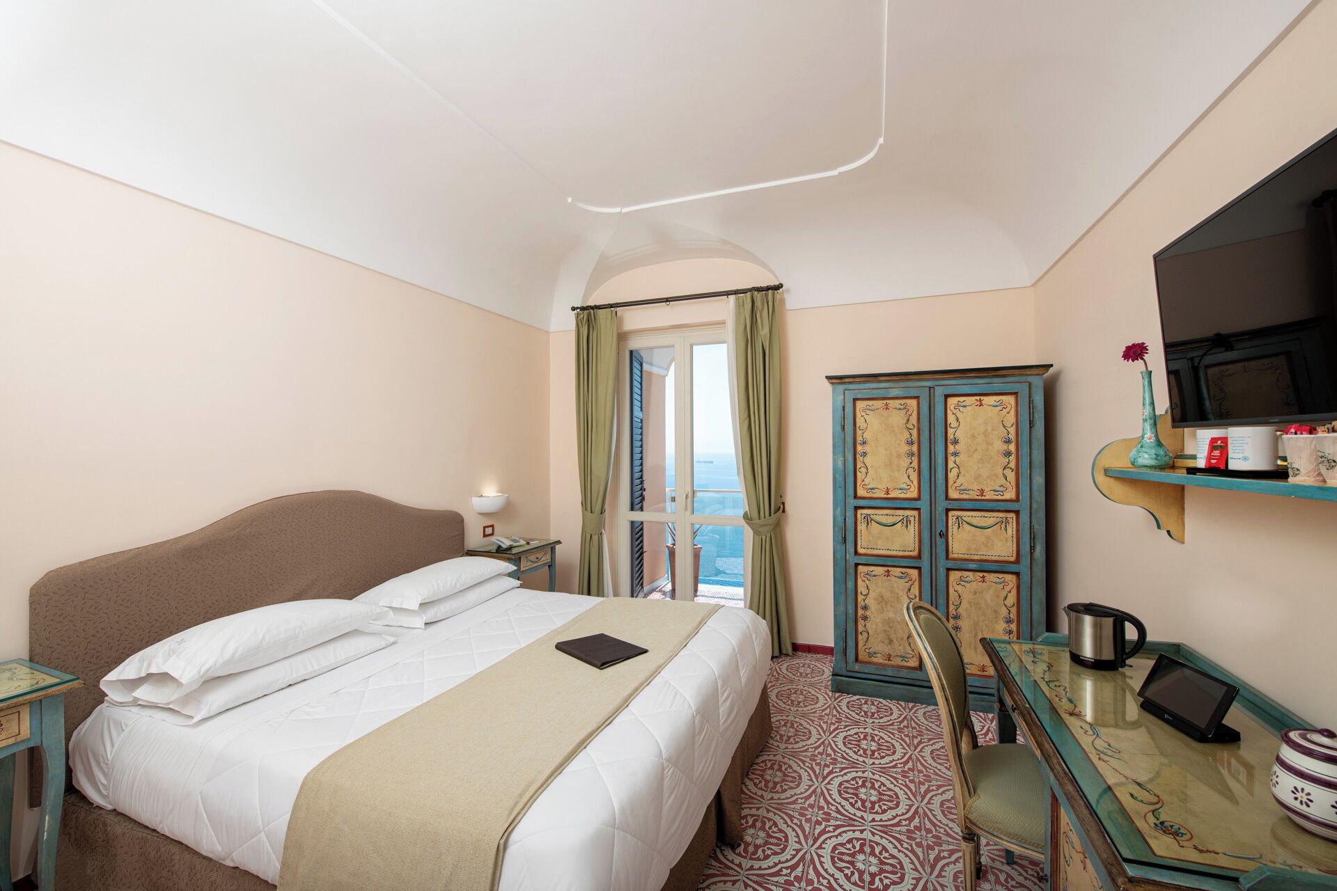 A hotel room with a bed, a desk with a chair, a TV, a cabinet, and a window with curtains.