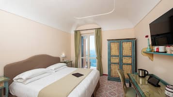 A hotel room with a bed, a desk with a chair, a TV, a cabinet, and a window with curtains.