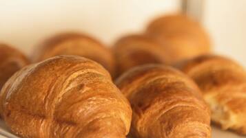 A close-up of several golden-brown croissants on a white plate.
