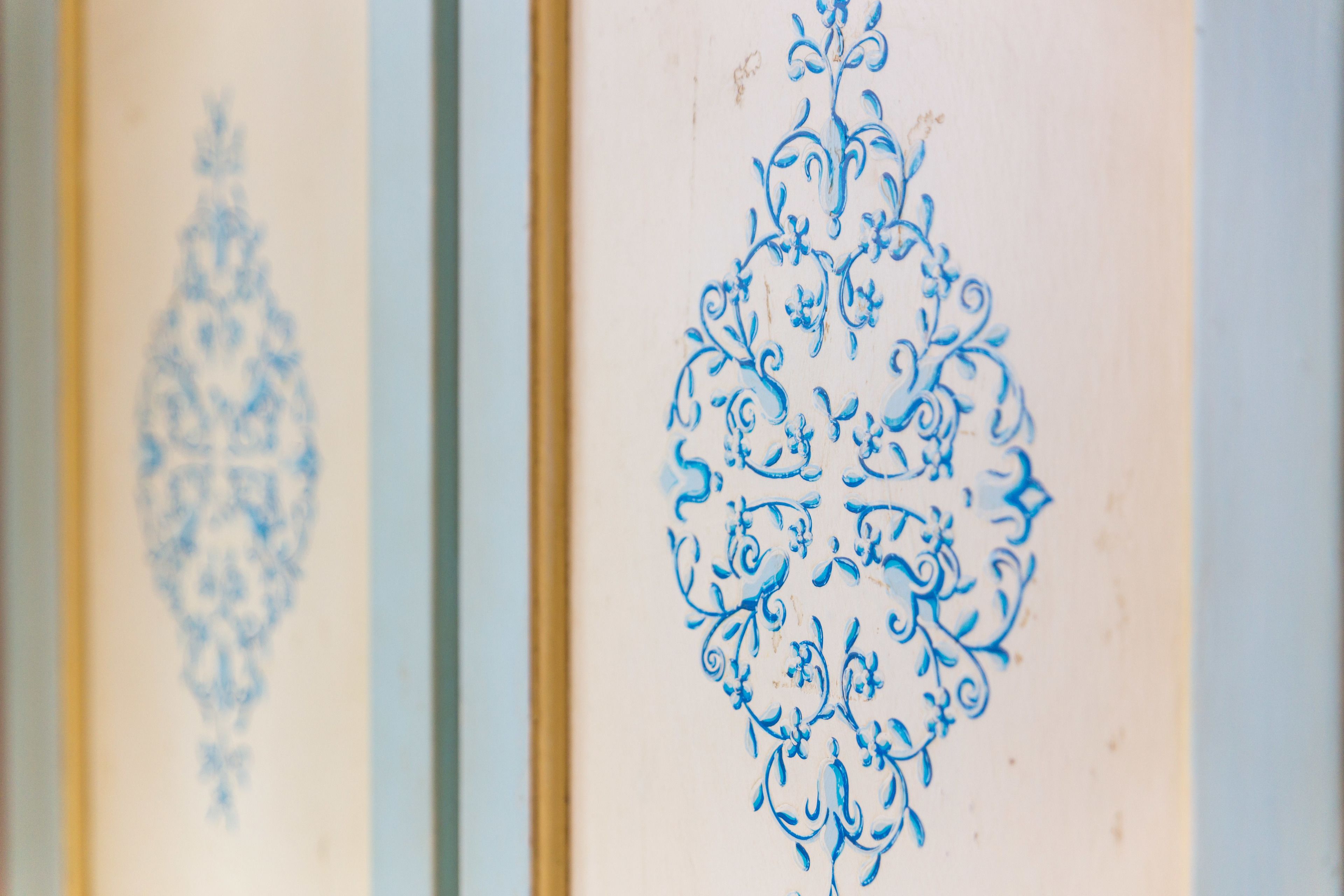 A close-up of ornate blue floral patterns on a wall.