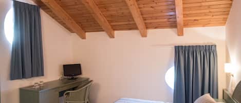 Un dormitorio con techo de madera, una cama con ropa de cama a rayas, un escritorio con una computadora y dos ventanas con cortinas.