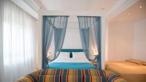 Una habitación con cama, sofá y cortinas translúcidas.