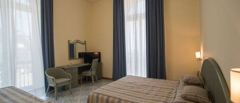 Une chambre d’hôtel avec deux lits, un bureau, une chaise et un téléviseur.