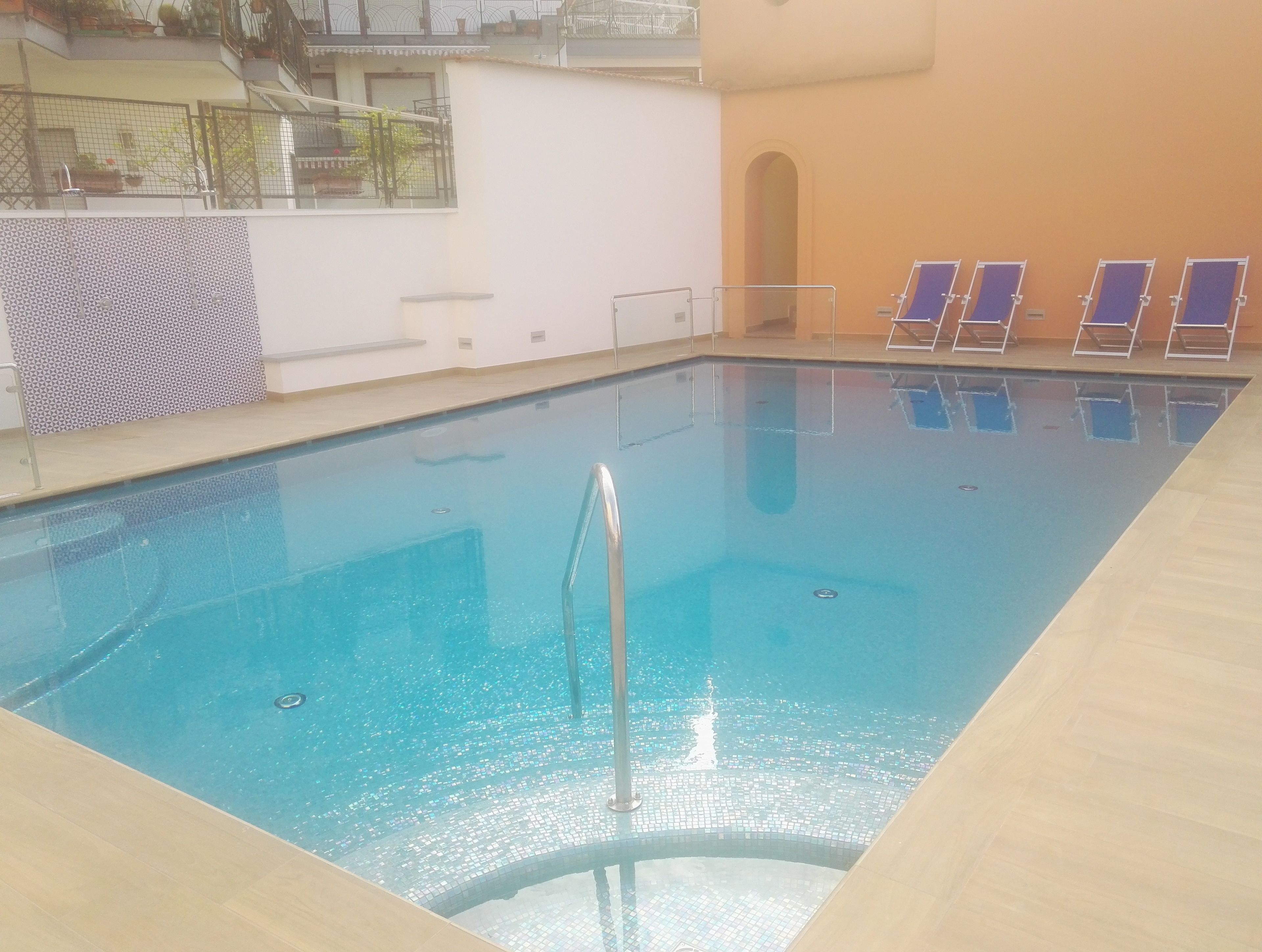 A rectangular indoor pool with clear blue water, surrounded by tiled walls and a wooden deck.
