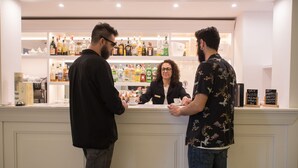Zona de bar con mostrador, estanterías llenas de botellas y una persona sirviendo bebidas.