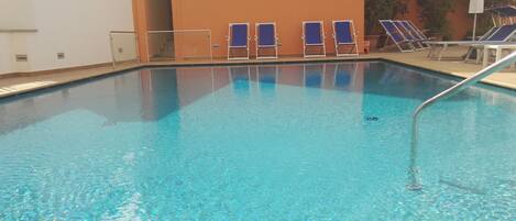 Piscine extérieure, parasols de plage, chaises longues