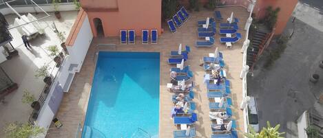A rooftop pool area with blue lounge chairs and a swimming pool.