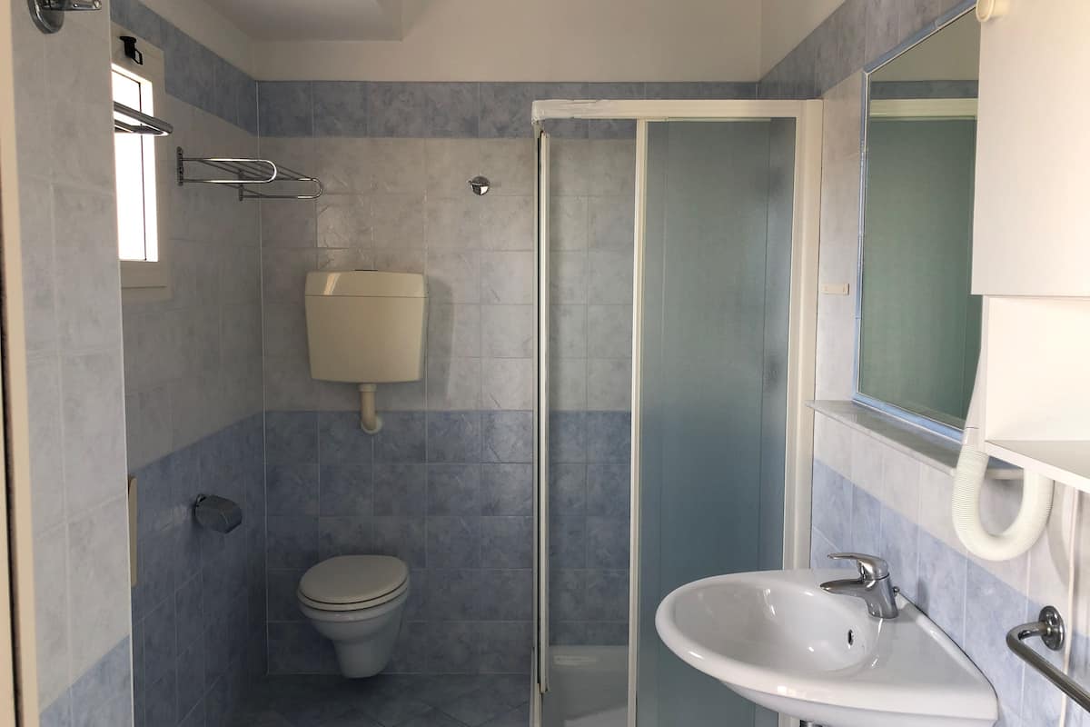 A bathroom with a toilet, a shower enclosure, and a sink.