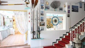 A staircase with red carpeted steps and a decorative vase. - Marconi (Cattolica)