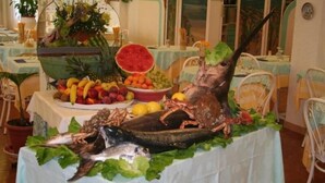A seafood display with various fruits and vegetables on a table in a dining area. - Marconi (Cattolica)