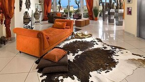 A modern living room with a sofa, a cowhide rug, and a view of the outdoors. - Hotel Thea (Gabicce Mare)