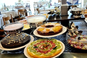 A buffet table with various dishes including a chocolate cake, a fruit tart, and a variety of desserts. - Hotel Thea (Gabicce Mare)