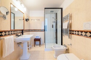 Un baño moderno con lavamanos, espejo, toallero, ducha e inodoro.