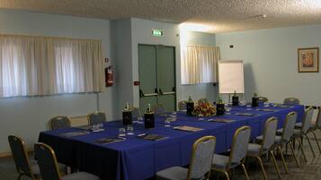 Une salle de conférence avec une longue table, des chaises et une porte.