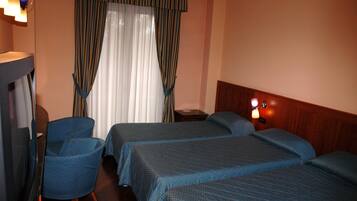 Habitación de hotel con dos camas, una silla, un escritorio y una lámpara.
