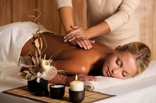 A person receiving a back massage in a spa setting with a candle and decorative elements on the table. - Hotel Michelangelo Palace (Terni)