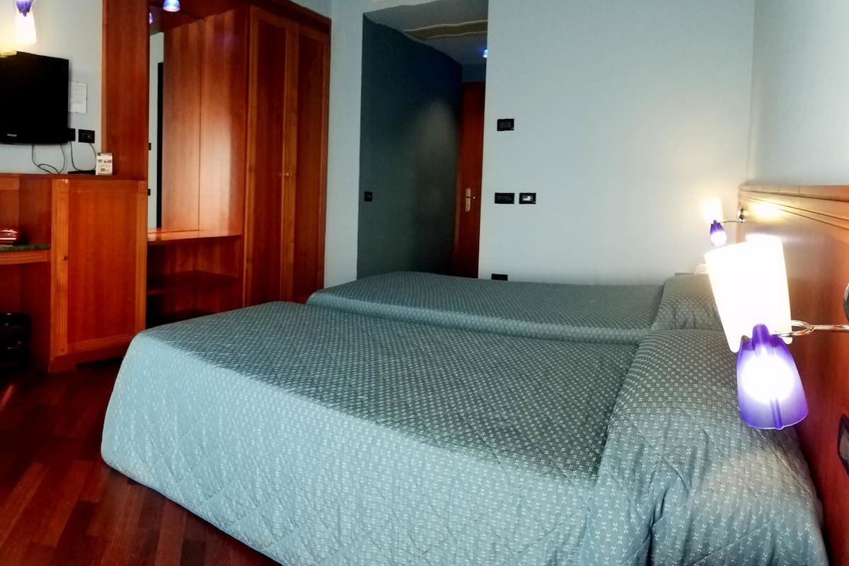 A room with a bed, a desk, a television, and a wooden wardrobe.