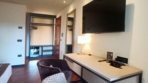 A hotel room with a bed, a desk, a TV, a chair, and a trash can. - Hotel Michelangelo Palace (Terni)